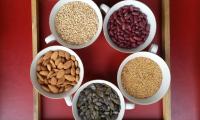 Oats, kidney beans, gold flax seeds, pumpkin seeds and almonds in raw food quality in 5 small bowls.