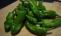 Raw green sweet peppers (Capsicum annuum) piled on a brown surface.