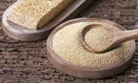 Amaranth, raw - Amaranthus caudatus - on a round wooden surface, with amaranth bars above.