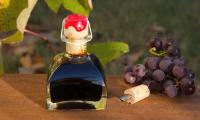 Balsamic vinegar (Aceto balsamico) in a square bottle surrounded by blue grapes.