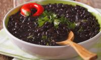 Black beans, cooked with plenty of water and chili peppers in bowl.