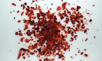 Chili flakes (Capsicum annuum), a small pile on a white background.