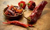 Chilli peppers, sun-dried in the bowl and next to it on the work surface.