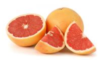 One sliced and one whole grapefruit with red pulp.