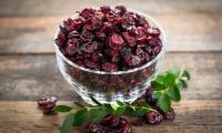 Cranberry: cranberries dried in small glass bowl on brown wooden surface.
