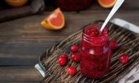 Cranberry-Orangen-Sauce mit Apfel in ein Glas gefüllt, mit einigen Cranbeeren darum herum.