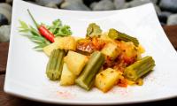 «Curry indiano con baccelli di moringa, patate e pomodoro» finito e servito su un piatto.