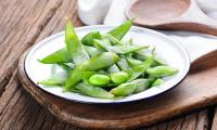 Edamame, frozen, blanched (organic?) On a light plate. These are soybeans harvested unripe.