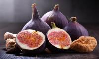 Three raw figs (Ficus carica) plus one cut open, next to two dried ones.