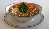 Фото готового блюда "Холодный суп из авокадо и огурцов с кольраби" в фарфоровой тарелке.