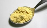 Spoon with yellowish mustard powder made from white mustard (Sinapis alba).