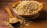 Pearl barley, raw: In wooden spoon and wicker basket, grains scattered next to them.