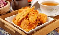 Mango, dried - Mangifera - in a white bowl in a serving board with a cup of tea.