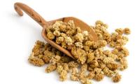 Dried (white) mulberries on a wooden ladle and around it on a white background.