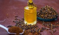 Ground cloves (Syzygium aromaticum) in a spoon, right next to dried cloves and clove oil.