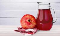 Pomegranate on napkin, glass carafe with classic pomegranate syrup next to it.