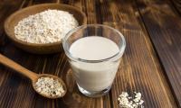 Vegan oat cream or oat cuisine in a drinking glass, with oat flakes around it.