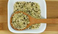 Hemp seeds, peeled, raw - Cannabis sativa - in white porcelain bowl with wooden spoon.