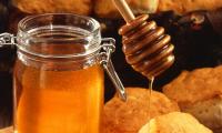 On the left, bee honey in a glass with a honey dripper on the right.