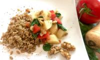 Готовое блюдо «Овощная зеленая спельта с пастернаком, шпинатои и орехами» на белой тарелке.