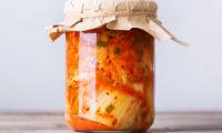 Homemade traditional Korean kimchi coleslaw in a glass on a wooden table.