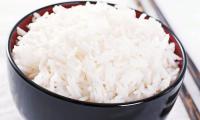 Липкий рис, белый, приготовленный в черной миске с двумя палочками для еды рядом с ним.
