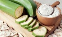 Cooking banana, raw, partly sliced, next to processed slices and flour from plantains.