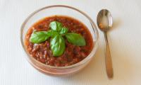 Готовый томатный соус с тамариндом, сервированный в чашке и украшенный базиликом.