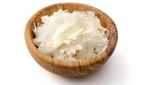 Coconut chips (Cocos nucifera) heaped in a wooden bowl.