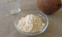 Coconut flour in a glass bowl (Cocos nucifera): in the background, coconut oil on the left and a whole coconut on the right.