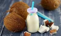 Coconut milk is pulp mashed with water, here in bottle, next to coconut and pieces.