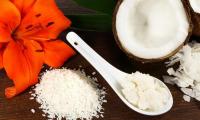 Coconut butter - Cocos nucifera: Coconut butter in a white spoon, surrounded by coconut nibs etc.