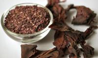 Dulse (ragweed), dried in flakes in a glass bowl, with whole pieces of red alga around it.