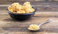 Lecithin from soybeans in black bowl with filled spoon in front of it.