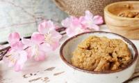 Miso paste in a bowl with flowers and soybeans, the raw material, on the top right.