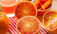 Orange, roh, mit Schale - Citrus sinensis: aufgeschnittene Früchte, dahinter Orangensaft.