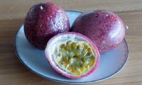 Ripe passion fruit (Passiflora edulis) on a plate — a half of a passion fruit is shown in front