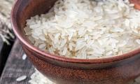 Long grain rice, white, raw - Oryza sativa L. - in a brown bowl.