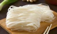 Reisbandnudeln bereit zum Garen, auf Küchenbrett liegend. Reisnudeln sind schmaler.
