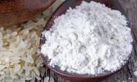 Rice flour, white, (gluten-free, raw, organic?) Heaped in wooden spoon.