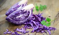 Rotkohl bzw. Blaukraut, roh - Brassica oleracea (Capitata Group), aufgeschnitten auf Tisch.