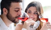 A young couple is tasting red table wine during a wine tasting.