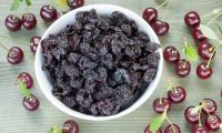 Dried sour cherries (Prunus cerasus) in a white ceramic bowl, next to fresh sour cherries.