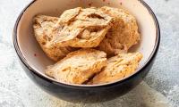 Five pieces of seitan, i.e. wheat gluten, in a brown ceramic bowl.