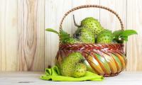 Soursop (graviola, guyabano) - Annona muricata - in a woven basket, a fruit in front of it.