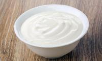 Vegan sour cream in white bowl on wooden Table with raw surface.