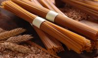 Wholemeal spaghetti to roll bundled next to wheat grains and ears of corn.