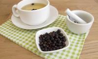 Common juniper; juniper berry—Juniperus communis in a bowl, a mortar on the right, and berry tea.