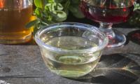 White vinegar from grapes in glass bowl (white wine vinegar), behind right half-full wine glass.