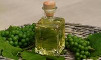 Grape-seed oil in a glass bottle with plastic grapes in a basket.